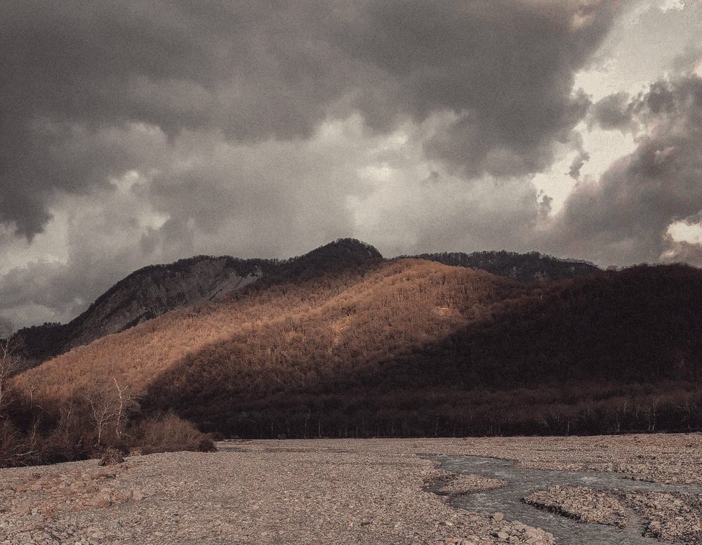 Storm clouds over a lit hillside